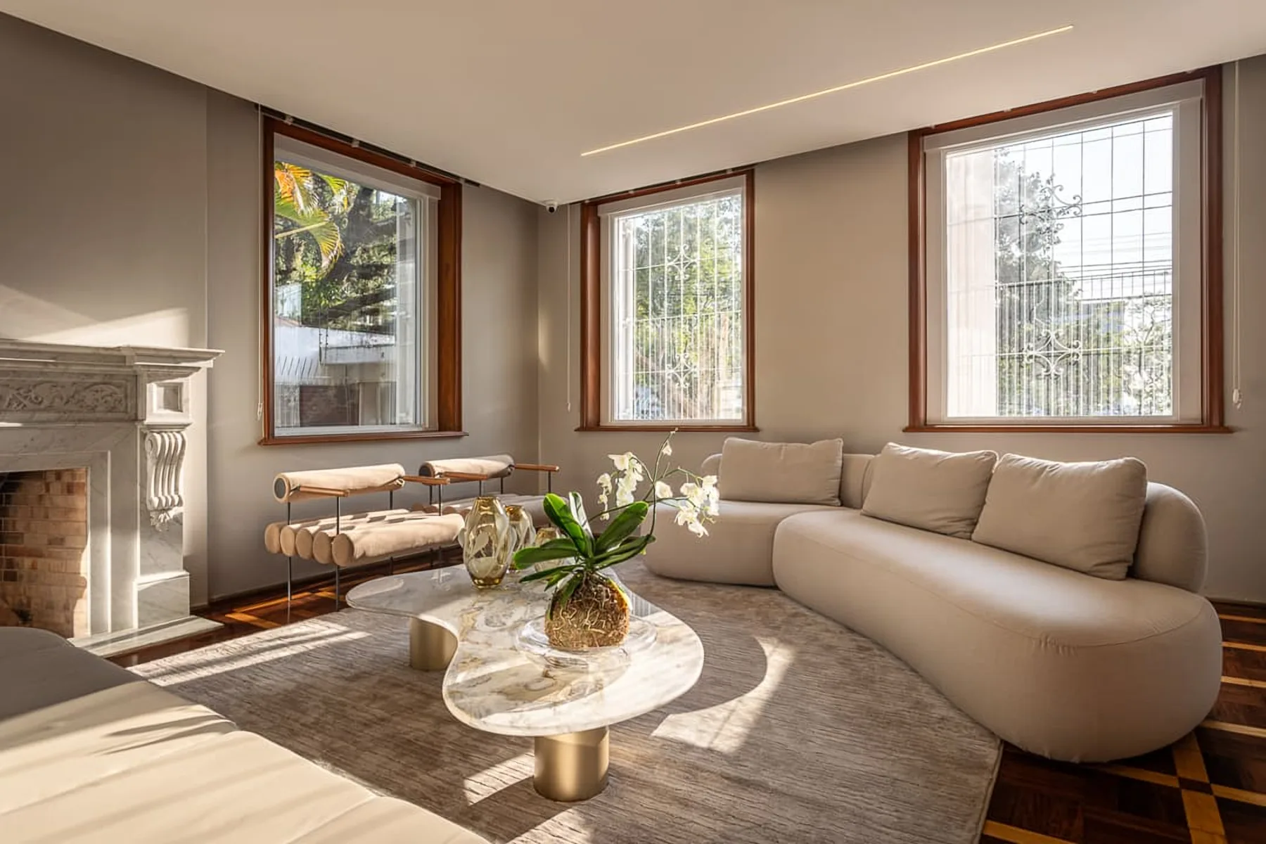 Sala de estar com lareira de mármore, sofá curvo e mesa de pedra